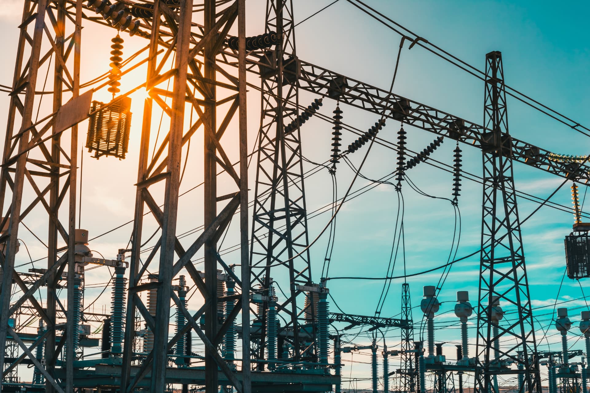 High-voltage transmission towers and substation equipment at sunset