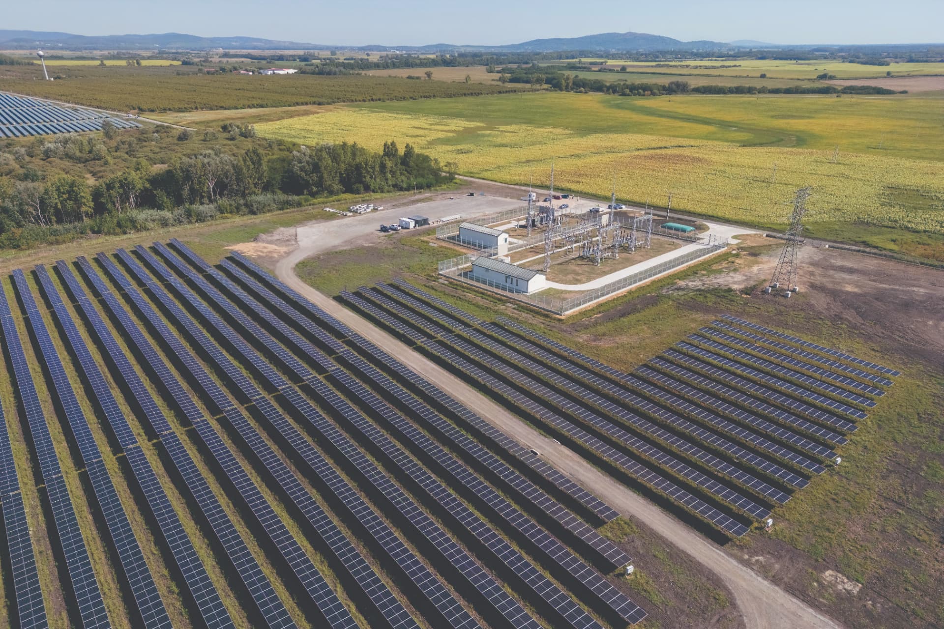 Aerial view of a large solar farm and substation surrounded by farmland