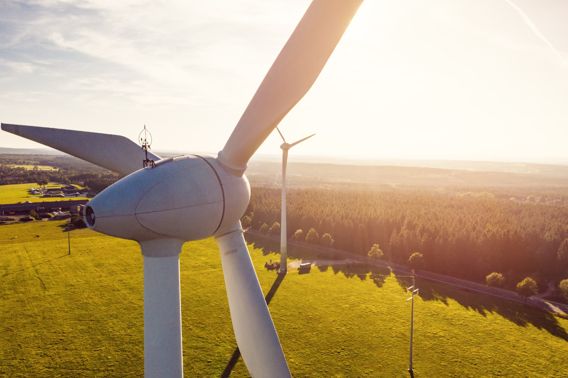 Aerial view of a wind turbine nacelle above green farmland at sunset