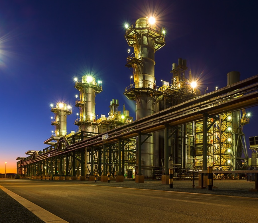 Gas-fired power station lit up at dusk with pipe racks in the foreground